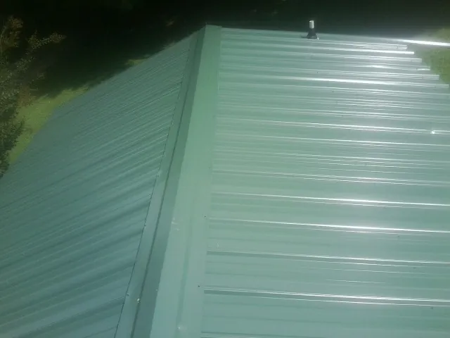 New green metal panels meeting at the ridge of a roof — Flat Roof Repair work by our crew in Dover Plains