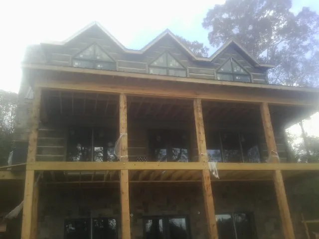 Dormers and porch framing on a large log home under construction — Roof Coating work by our crew in Dover Plains