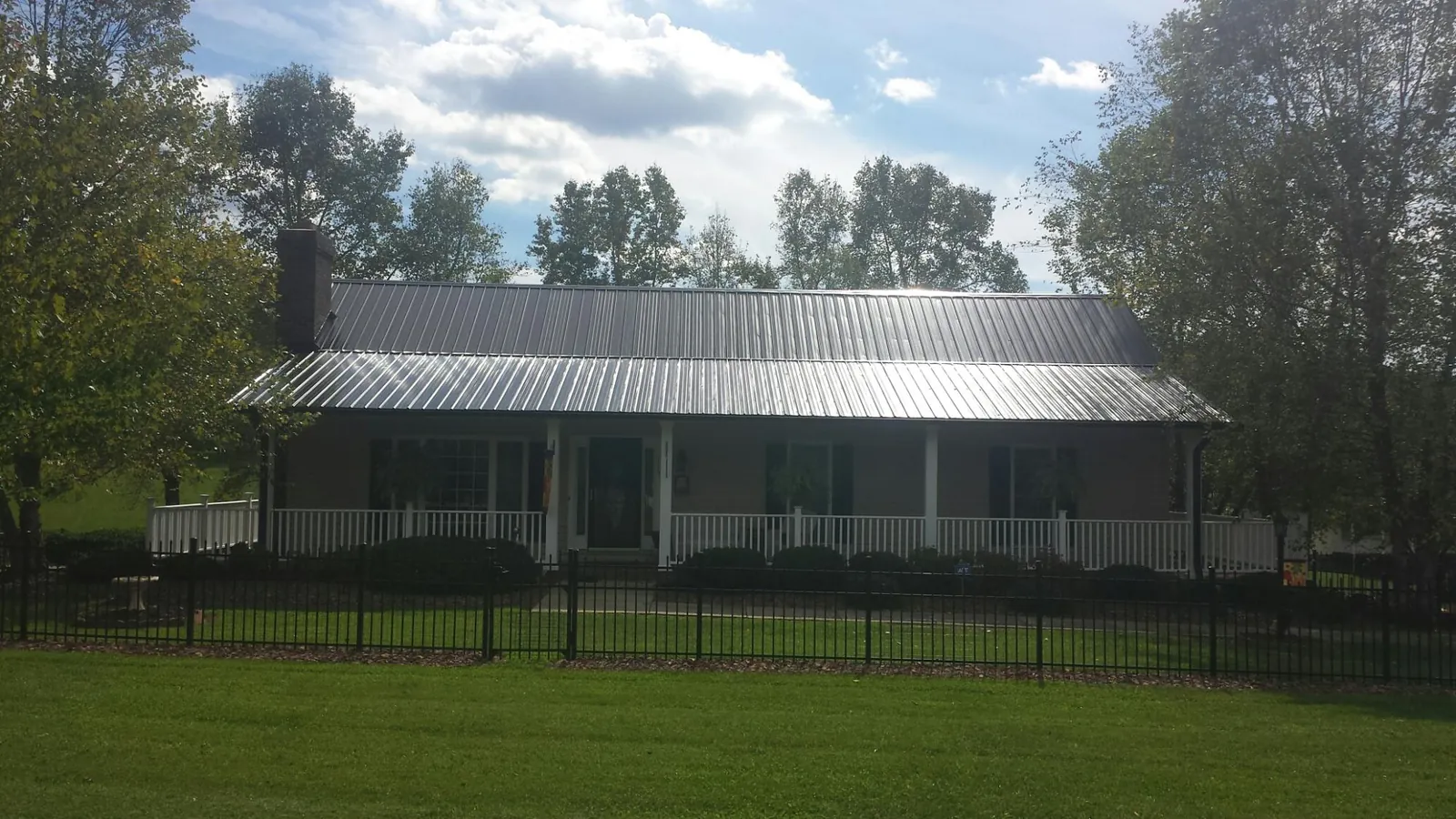 Gray metal roof on a brick ranch with a full width front porch — Gutter Guard Installation work by our crew in Dover Plains