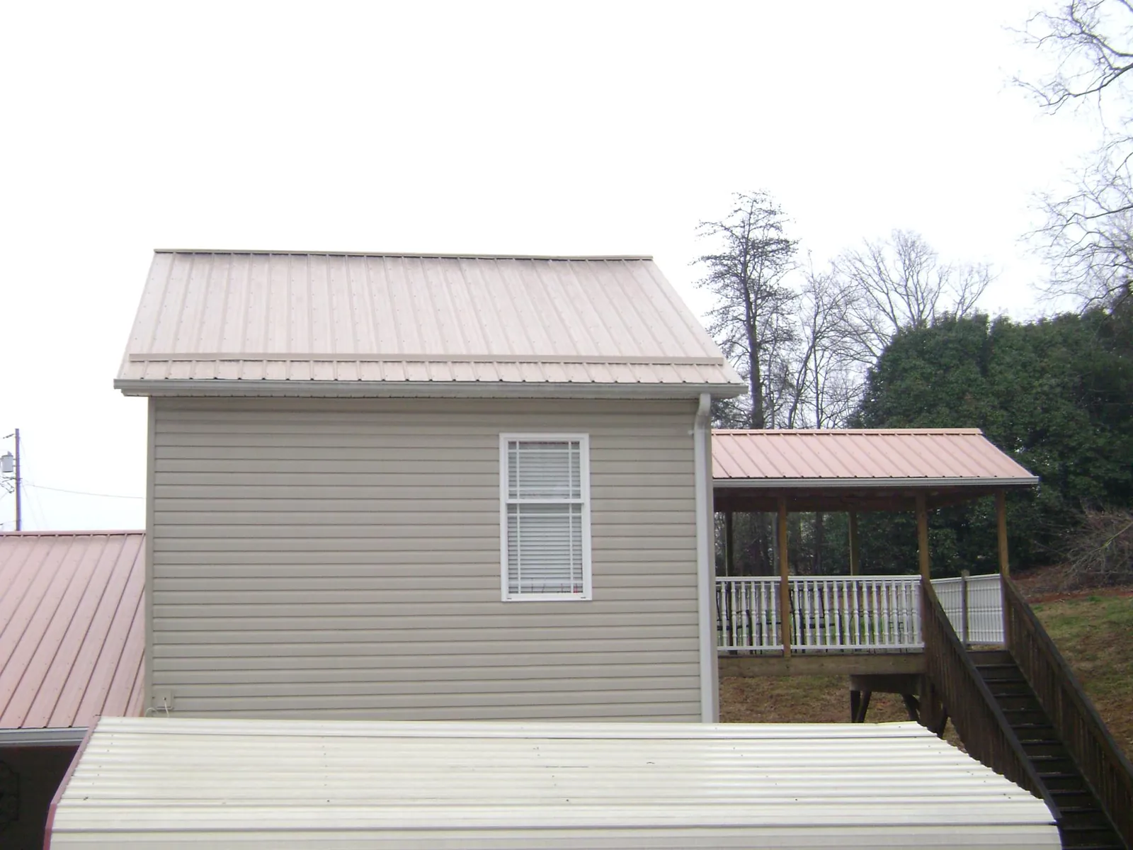 Tan metal roofs on a two story addition and attached porch, from a Roof Replacement job in Dover Plains
