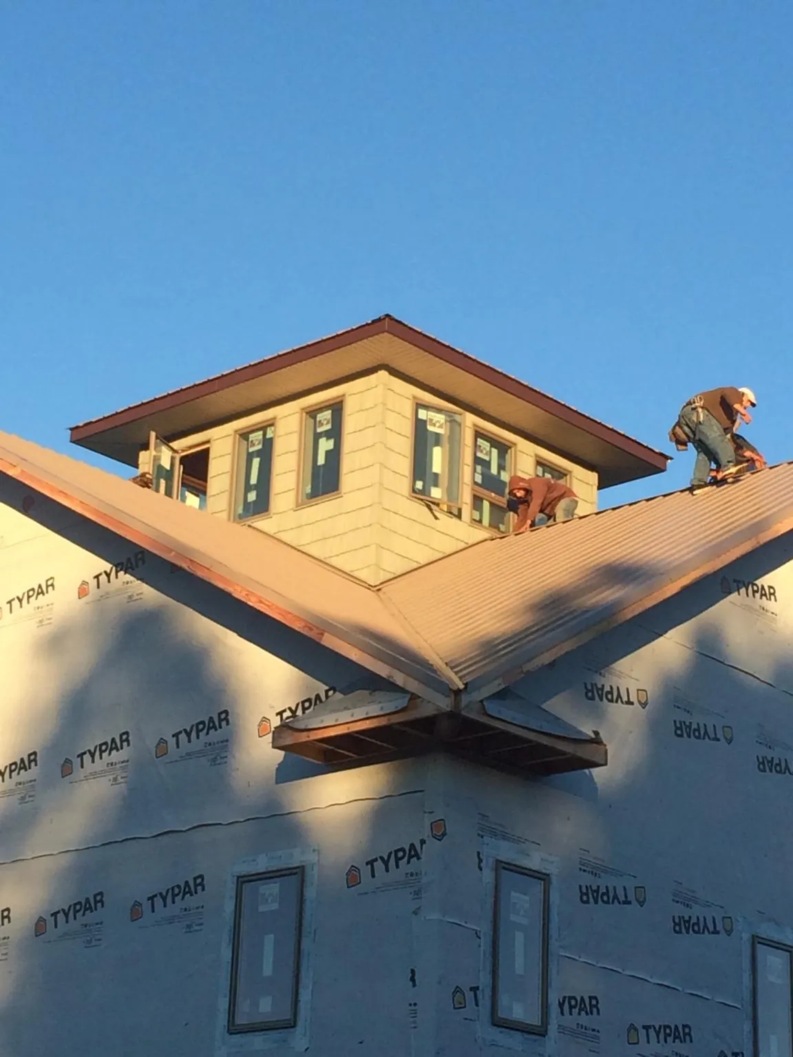Roofers working around a rooftop cupola on a new metal roof at sunset — Roof Waterproofing in Dover Plains by Roofing Brothers